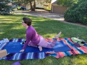 A woman wearing a purple sweater doing a yoga pose outdoors